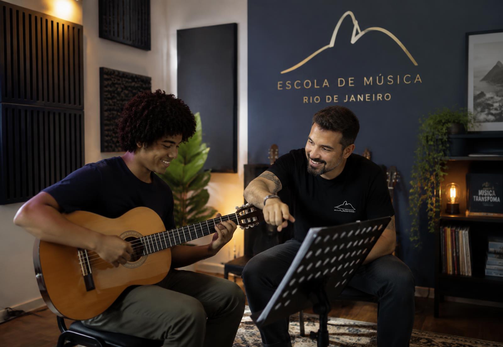 Professor orientando aluno em aula de violão em sala tratada acusticamente